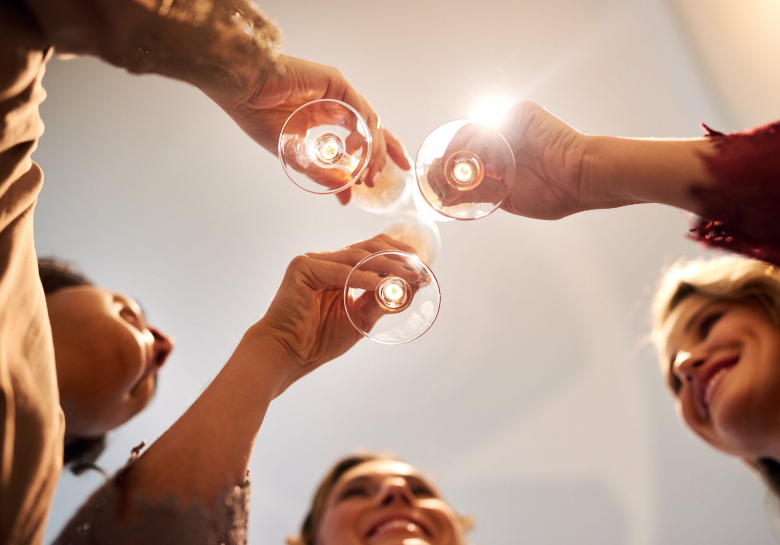 People, smile and toast with champagne in glass for special event, reunion or celebration together. Women, friends and happy with alcohol in low angle for success, cheers or party on New Year at home.